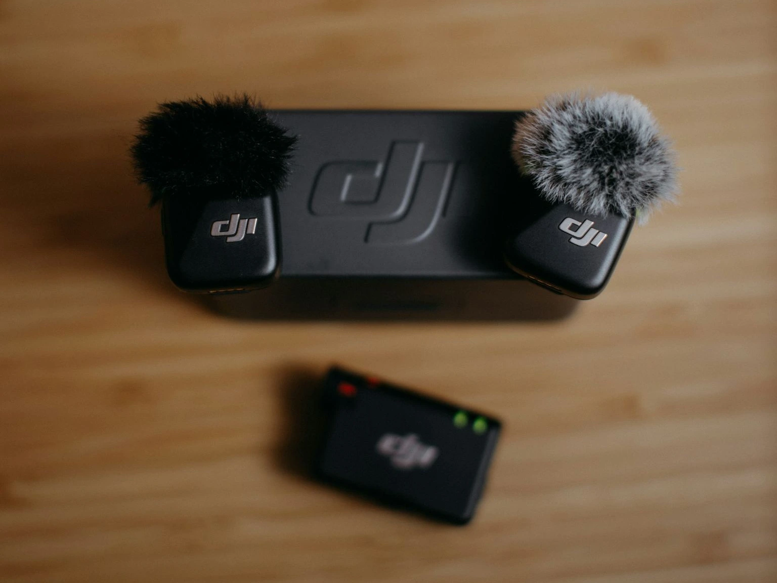 Dji microphones and receiver on wooden surface.